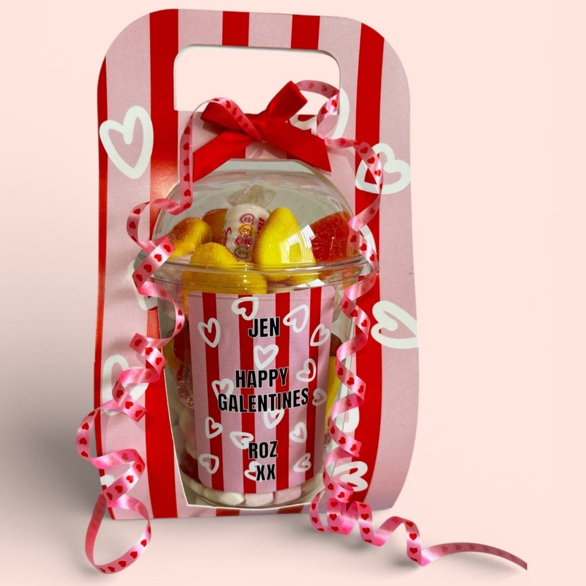 Valentine's Day gift set with a jar of candy and decorative packaging on a pink background