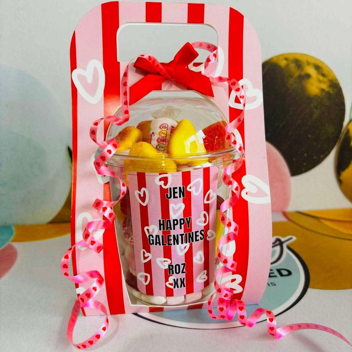 Valentine's Day themed candy jar with red and white striped design and pink bow.